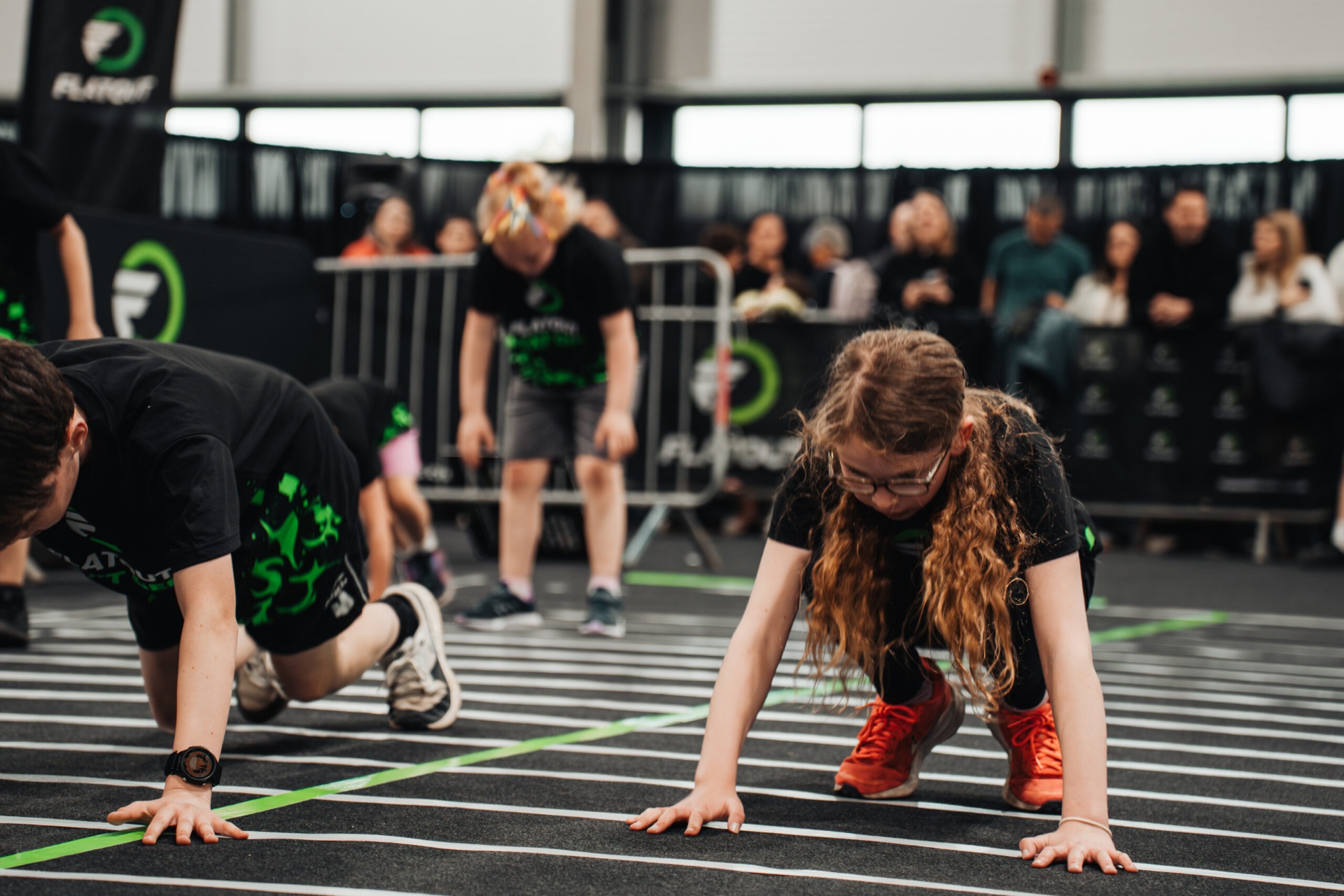Young athletes performing bear crawls on the Flatout NextGen race floor